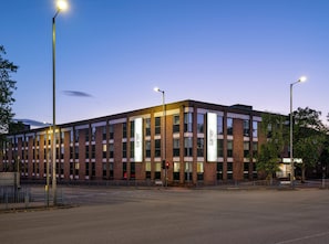 A modern building with a brick facade, large windows, and illuminated signage. - Garner Hotel Wolverhampton by IHG (Wolverhampton)