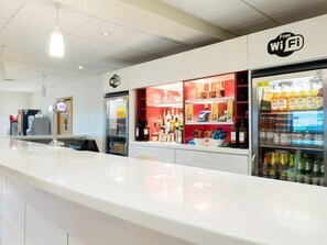 Un espace bar propre et moderne, doté d’un comptoir blanc, d’un mini-bar et d’un panneau indiquant que le Wi-Fi est gratuit.