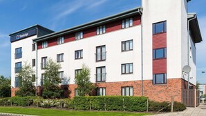 Een Travelodge hotel met een modern design, herkenbaar aan een plat dak, meerdere balkons en een bakstenen gevel.