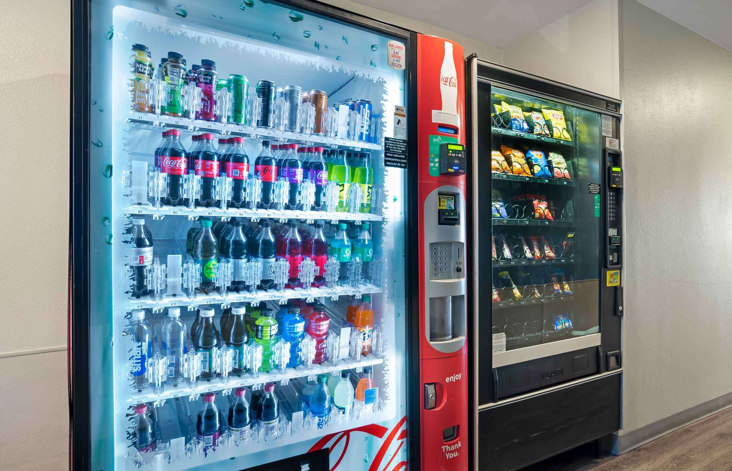 A vending machine with a Coca-Cola logo and a Coca-Cola branded vending machine next to it.