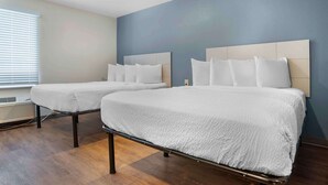 A hotel room with two beds, a large window with blinds, and a wall with a blue and white pattern. - Extended Stay America Select Suites - Fort Walton Beach (Fort Walton Beach)
