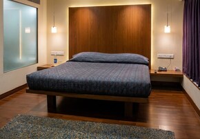 Una habitación de hotel moderna con una cama grande, mesitas de noche, un escritorio con teléfono y vistas a la ciudad.