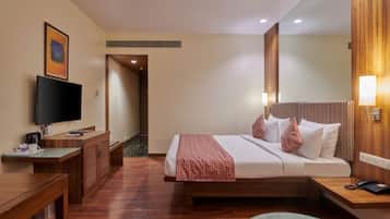 Una habitación de hotel con cama, mesita de noche, televisión y escritorio con silla.