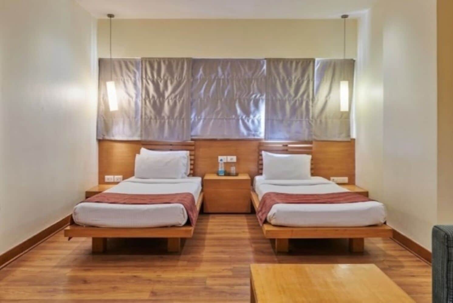 A double room with two beds, wooden headboards, a small table, and a mirror above the beds.