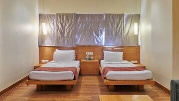 A double room with two beds, wooden headboards, a small table, and a mirror above the beds.