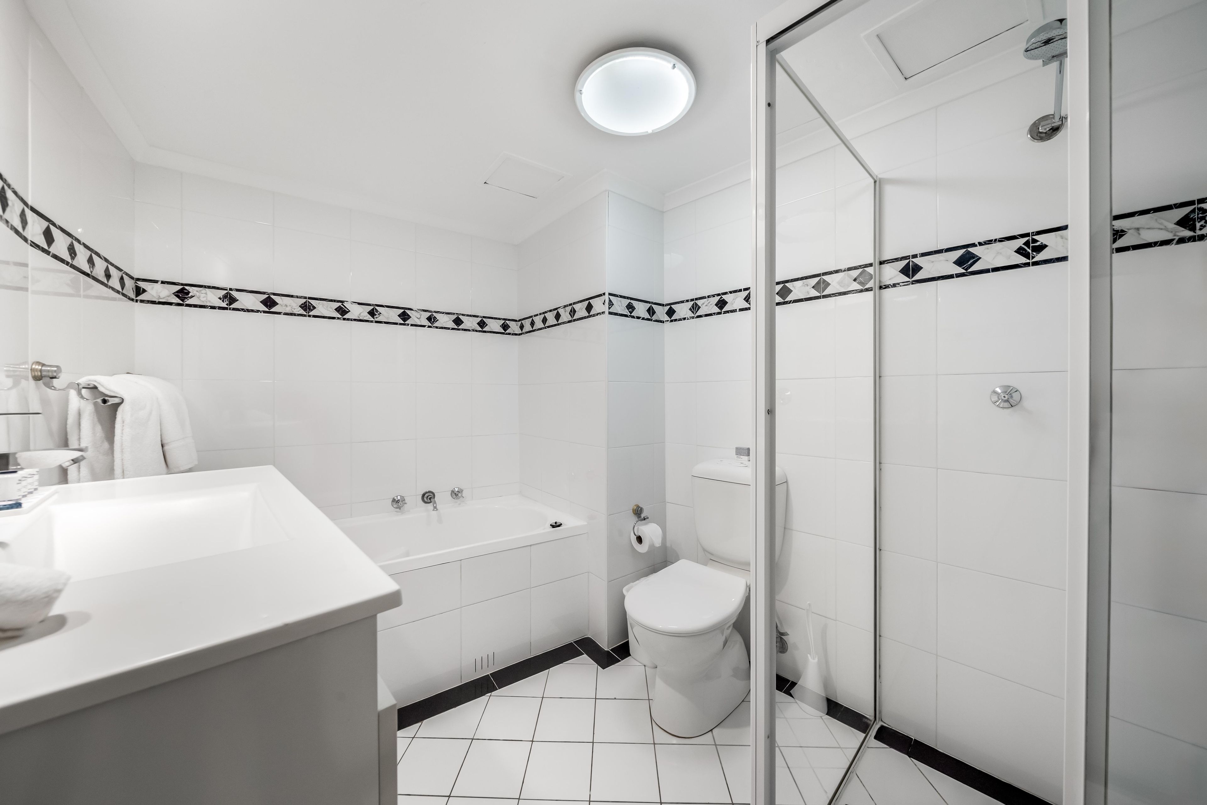 Een moderne badkamer met een bad, toilet en douche.