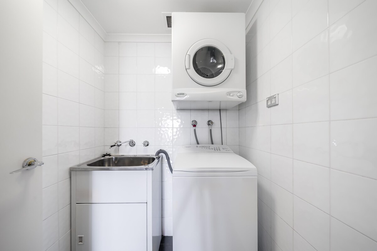 Un área de lavandería compacta con lavadora, secadora y lavabo.