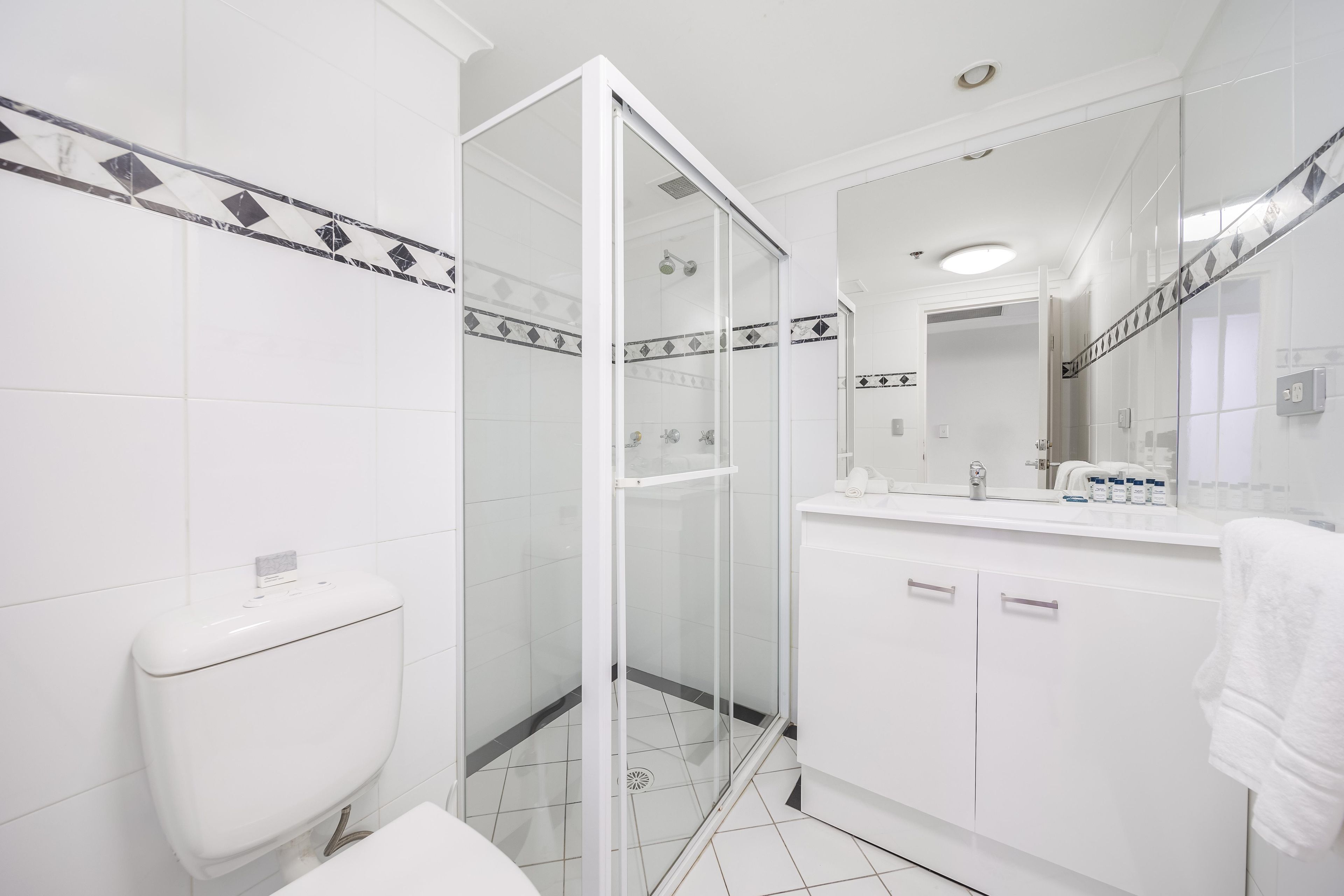 A modern bathroom with a glass-enclosed shower, white fixtures, and a tiled floor.