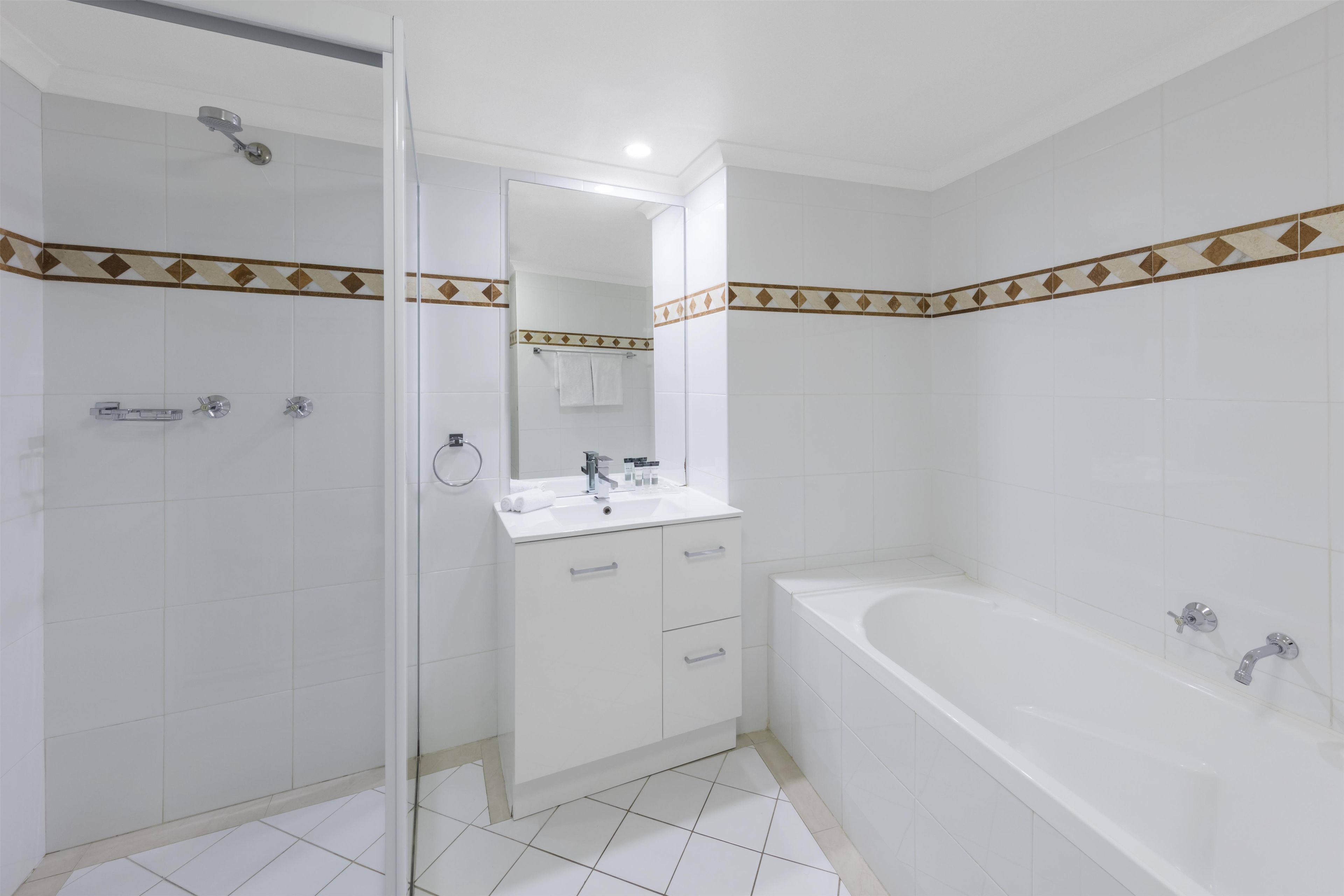 A modern bathroom with a glass shower enclosure, a white sink with a mirror, and a standalone bathtub.