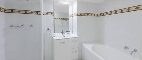 A modern bathroom with a glass shower enclosure, a white sink with a mirror, and a standalone bathtub.