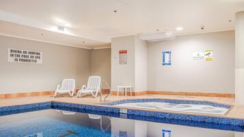 A swimming pool area with lounge chairs, a sign prohibiting diving or jumping, and safety notices.