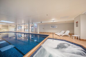 A swimming pool area with a clear water surface, a hot tub, and lounge chairs. - Oaks Sydney Castlereagh Suites (Haymarket)