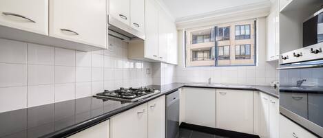 A modern kitchen with white cabinets, a black countertop, and a built-in oven.