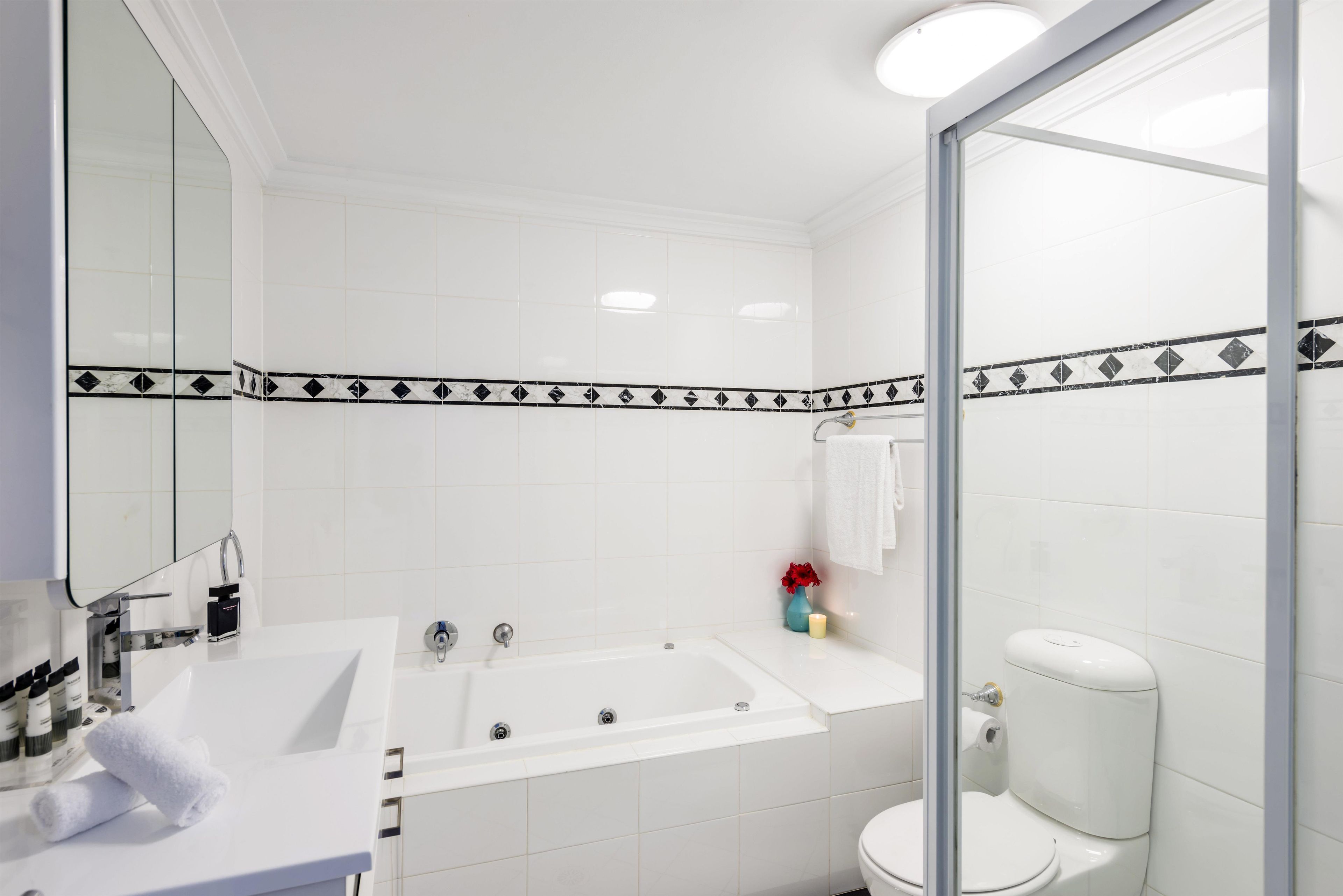 A modern bathroom with a white sink, a bathtub, and a toilet.