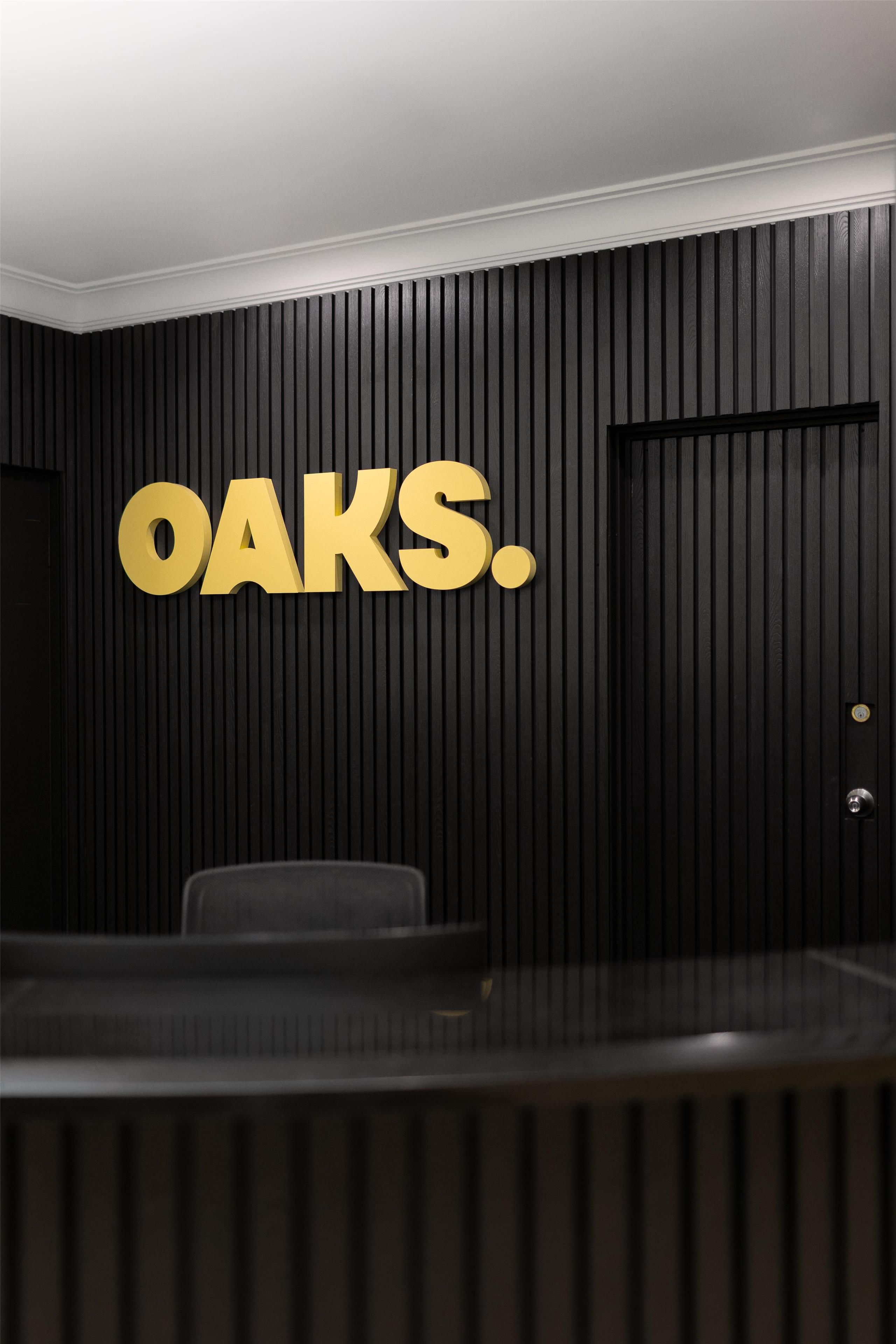 A conference room with a black panel wall and a large 'OAKS.' sign.