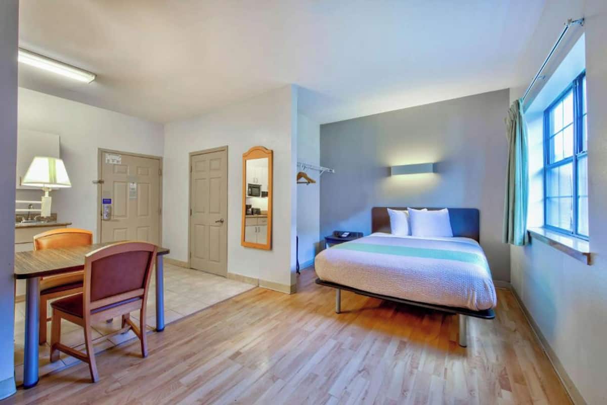 Una habitación de hotel pequeña con cama, escritorio y silla.
