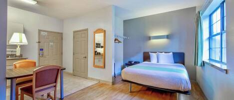 A compact hotel room with a bed, a desk, and a chair.