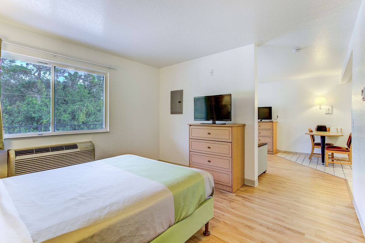 A bedroom with a bed, a TV, a desk, and a chair.