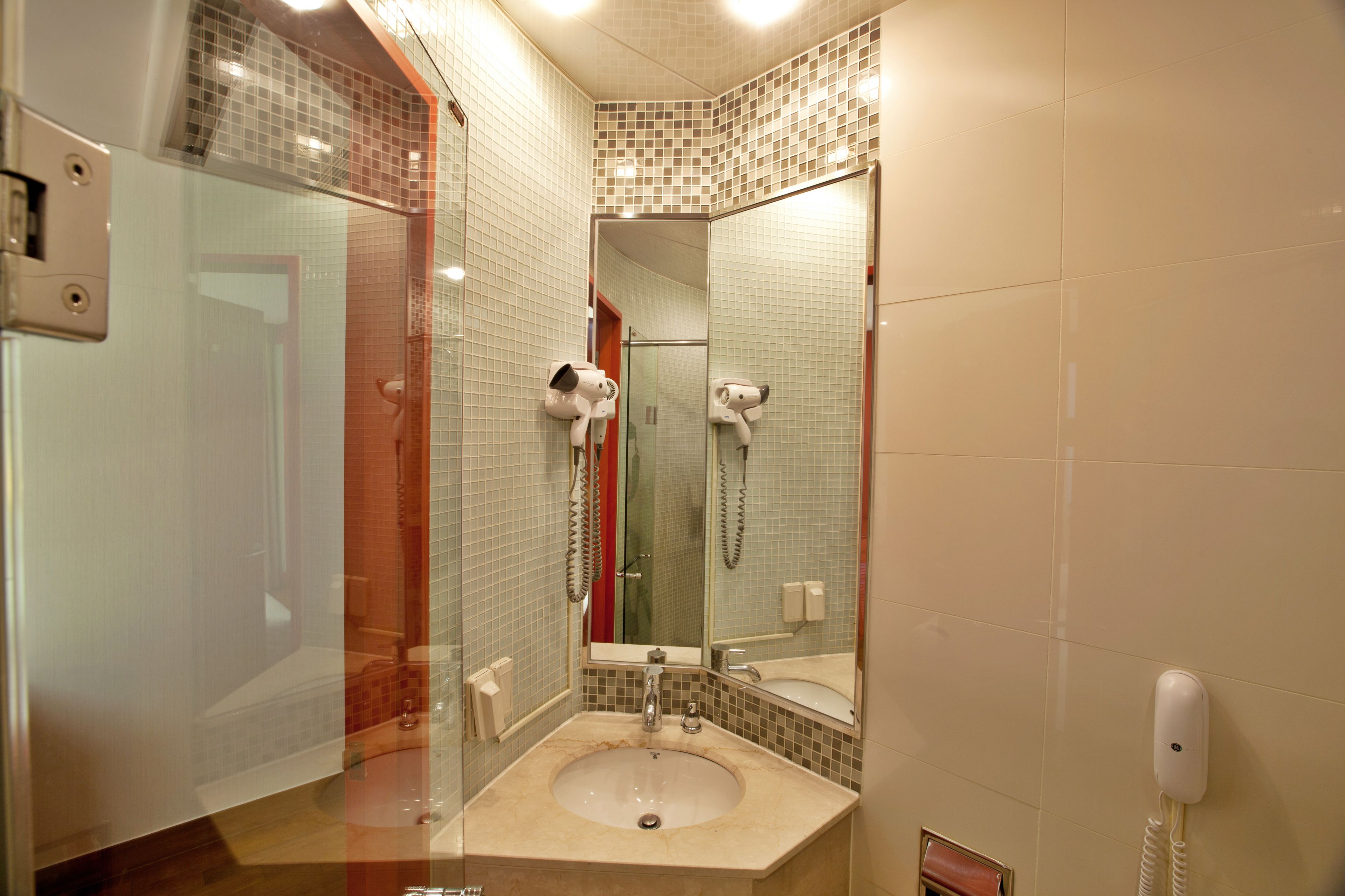 Un baño con lavamanos, espejo y secador de pelo.