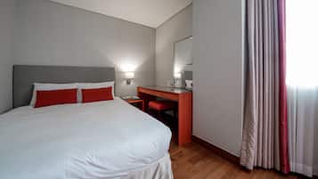 A hotel room with a large bed, a desk, and a mirror.