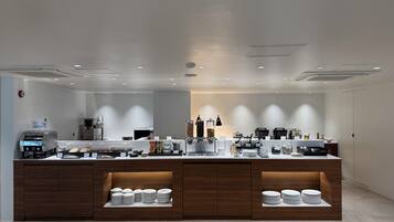A modern kitchen with a central island, equipped with a coffee machine, a food dispenser, and various kitchen appliances.