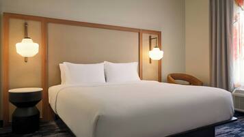 Una habitación de hotel con una cama grande, dos lámparas fijadas a la pared, una mesita redonda y una silla.