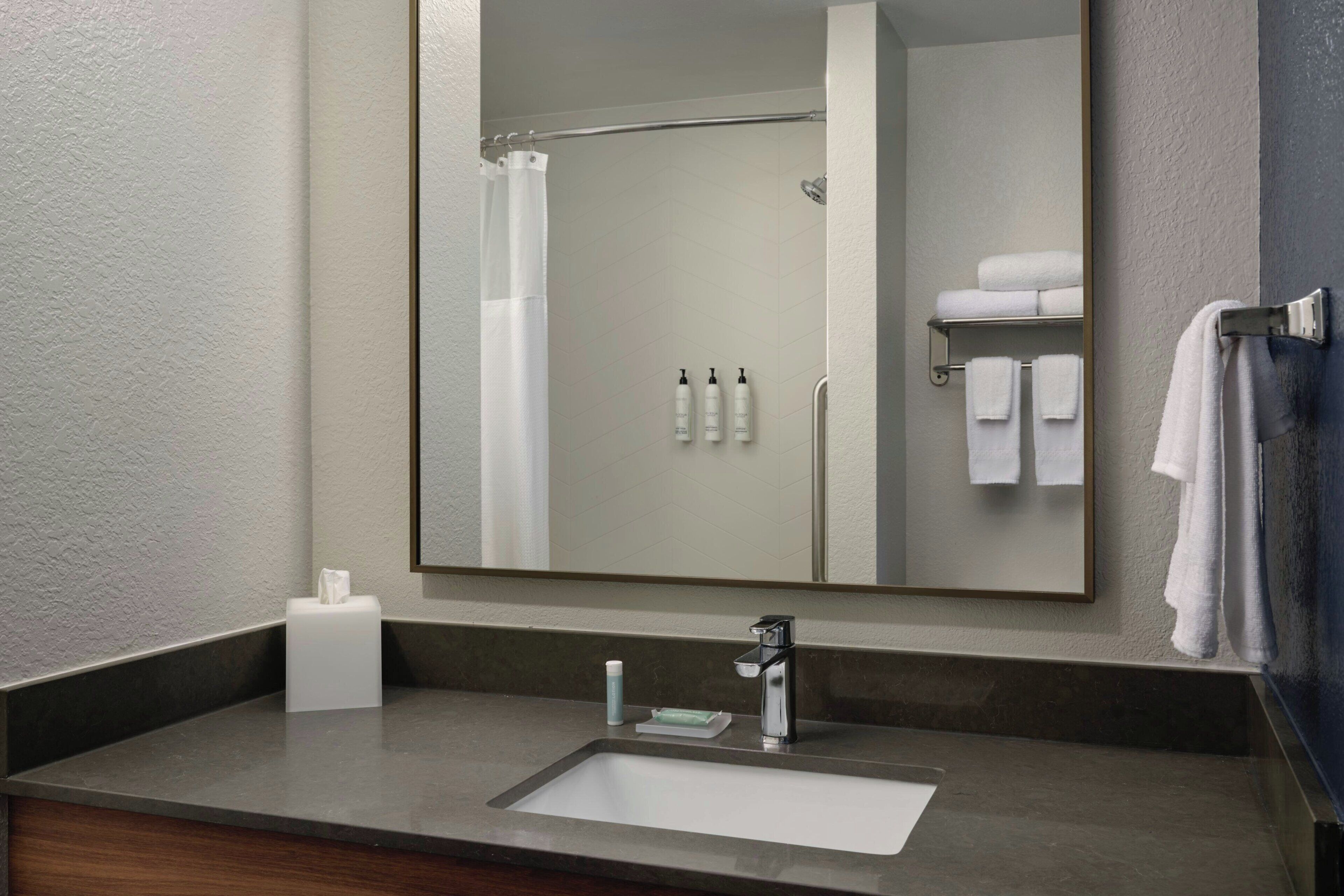 Une salle de bain équipée d’un lavabo, d’un miroir et d’un porte-serviettes.