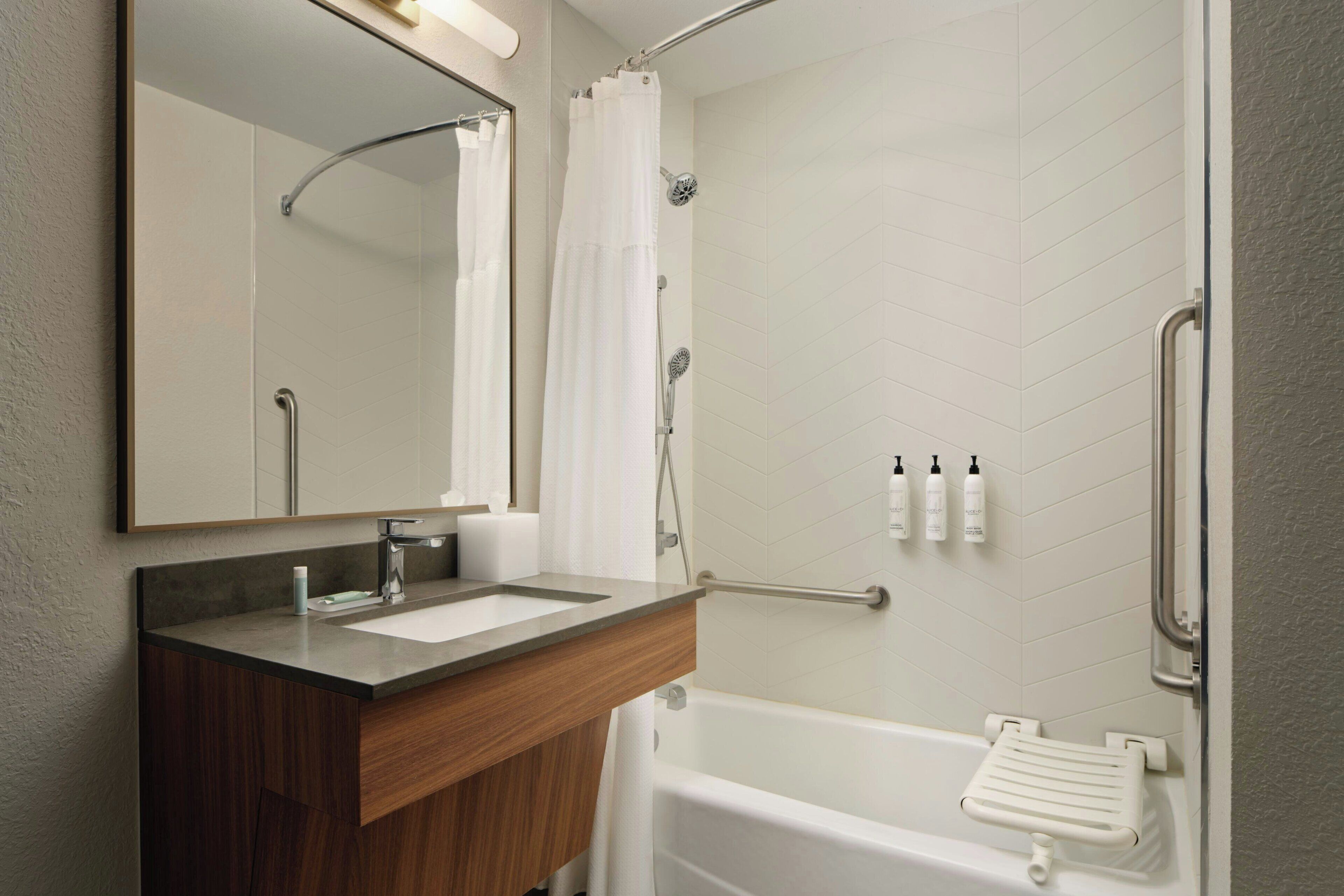 Een badkamer met een douche, wastafel, spiegel en bad.