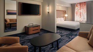 A hotel room with a bed, a TV, a desk, a sofa, and a coffee table.
