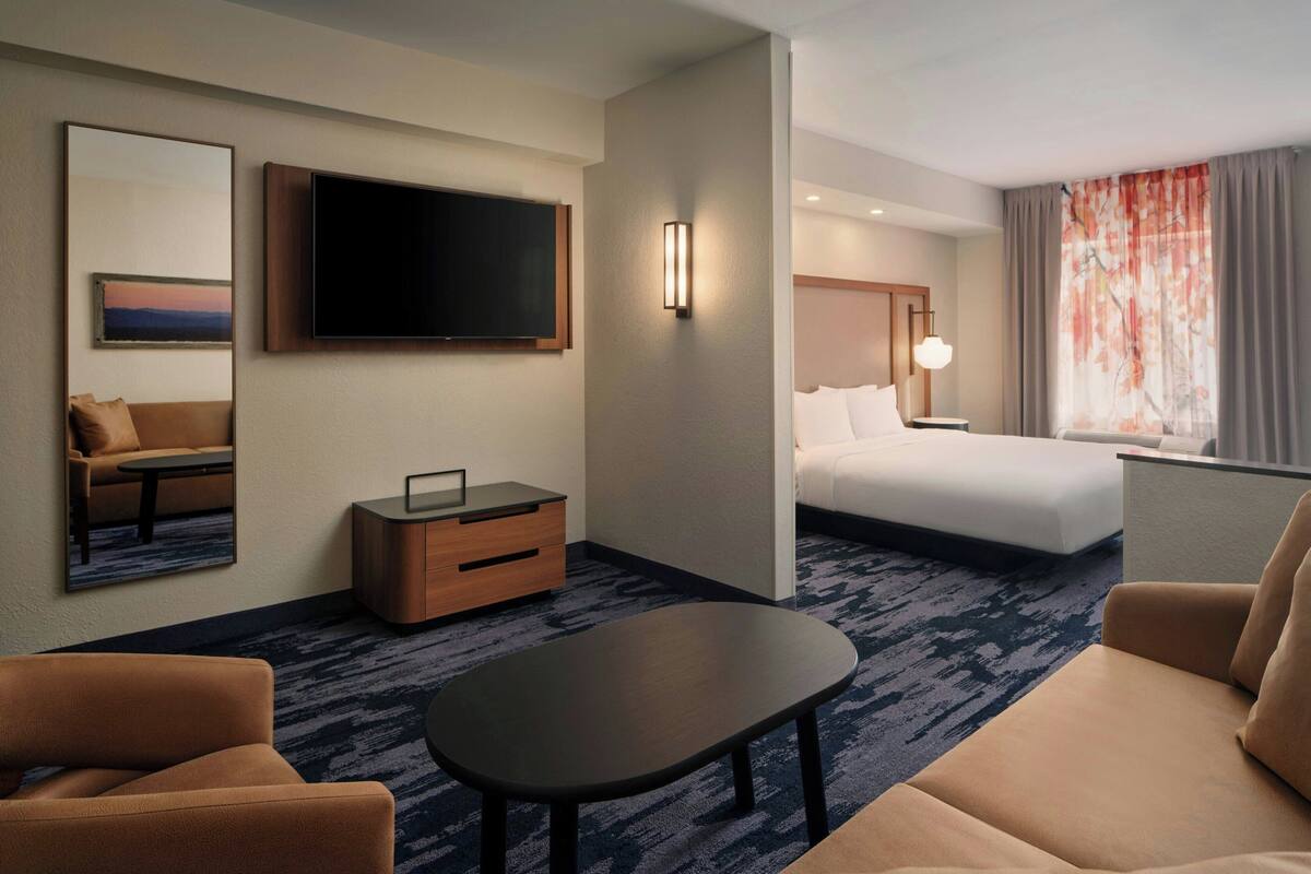 A hotel room with a bed, a TV, a desk, a sofa, and a coffee table.