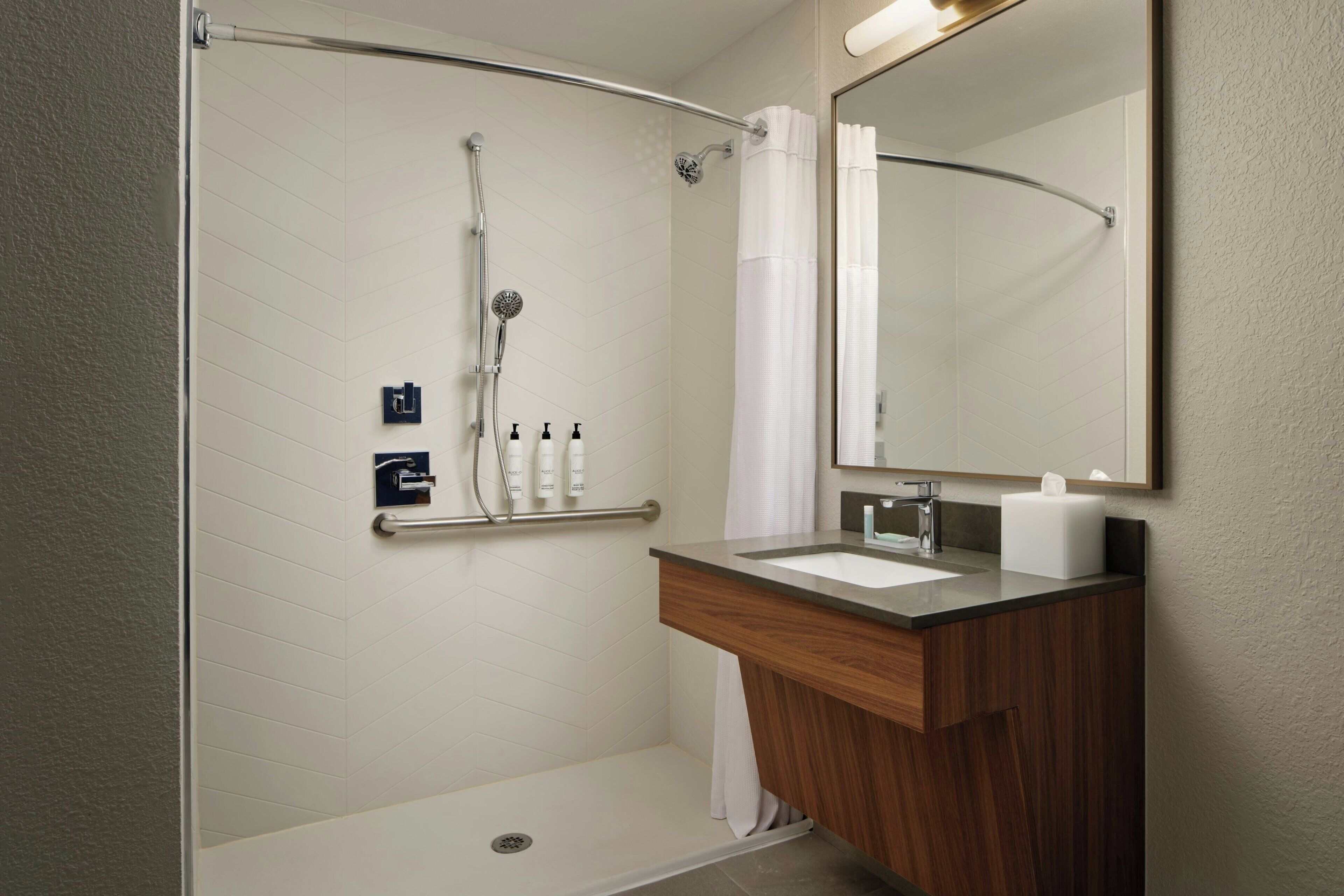 Ein modernes Badezimmer mit Dusche, Waschtisch und großem Spiegel.