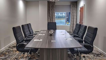 A conference room with a large rectangular table, six black chairs, and a modern ceiling light fixture.