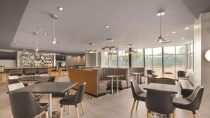 A modern dining area with high tables, black chairs, and a central seating area with a wooden partition. - Radisson Hotel Atlanta Airport (College Park)