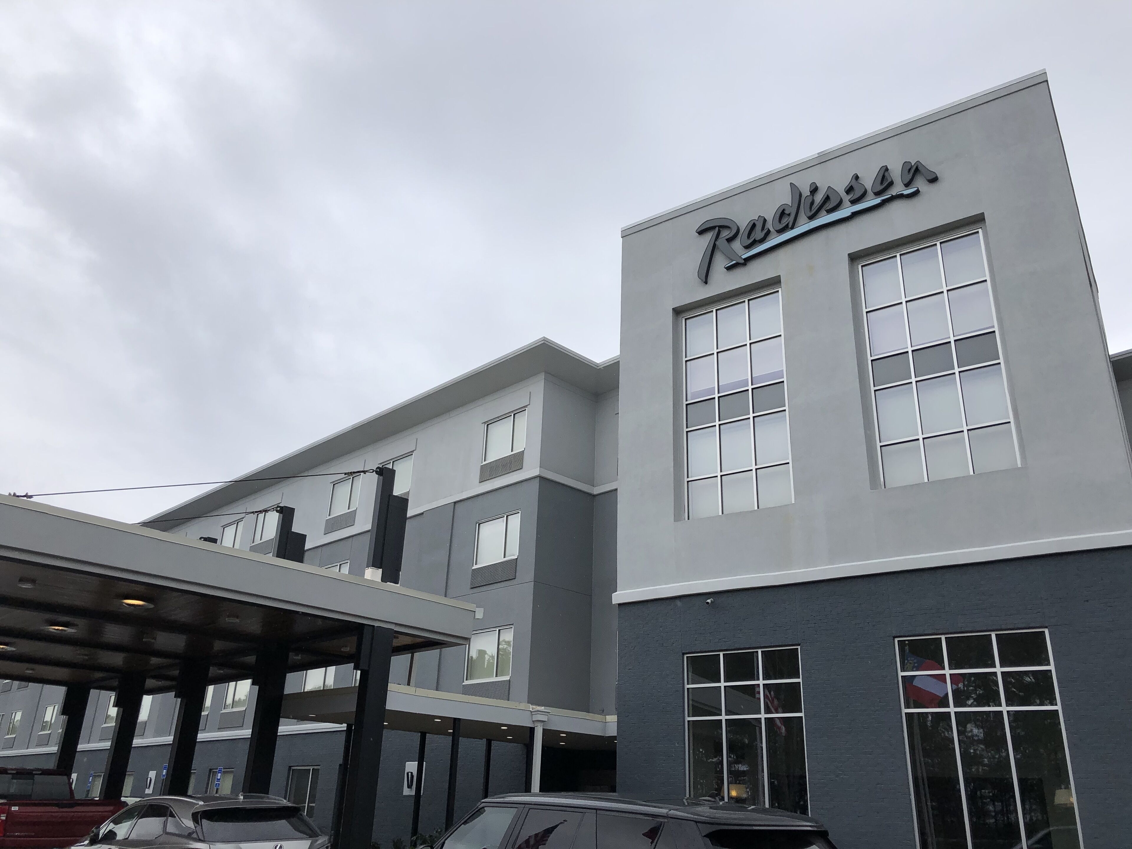 Een Radisson hotel met een moderne gevel, grote ramen en een overdekte parkeerplaats.