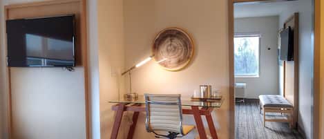 Un espacio de oficina moderno con un escritorio de vidrio, una silla de cuero y un televisor montado.