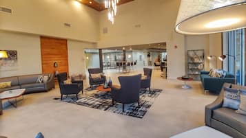 A spacious lobby with modern furniture, a large chandelier, and a view of the dining area.