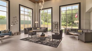A spacious living room with large windows, a modern chandelier, and a minimalist design. - Radisson Hotel Atlanta Airport (College Park)