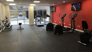 A gym with cardio machines, weight equipment, and a TV on the wall.