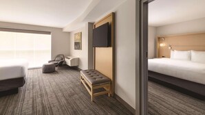 A hotel room with a bed, a bench, a desk, a chair, and a television. - Radisson Hotel Atlanta Airport (College Park)