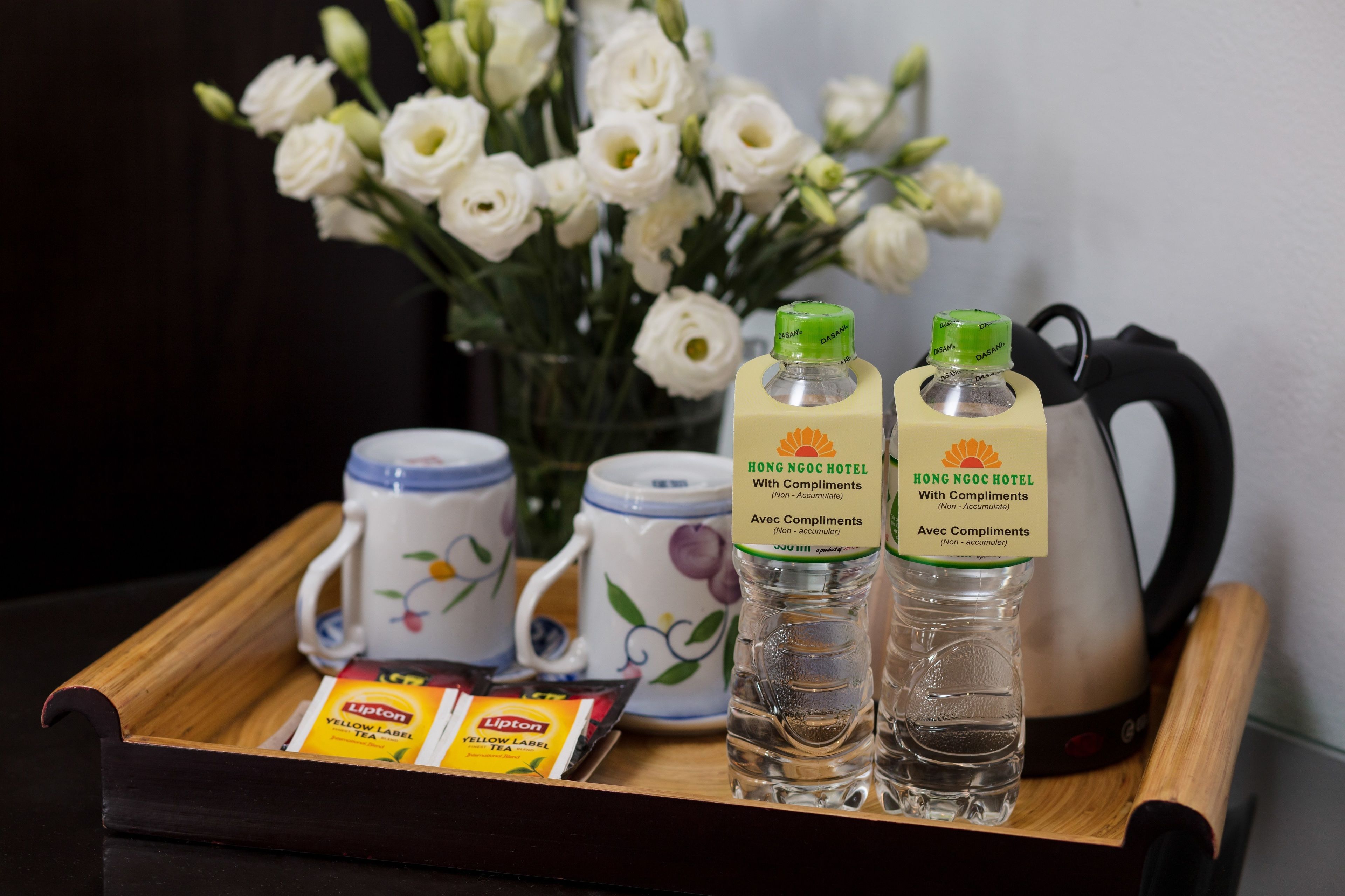 A tray with Lipton tea packets, two bottles of water, a mug, and a kettle.