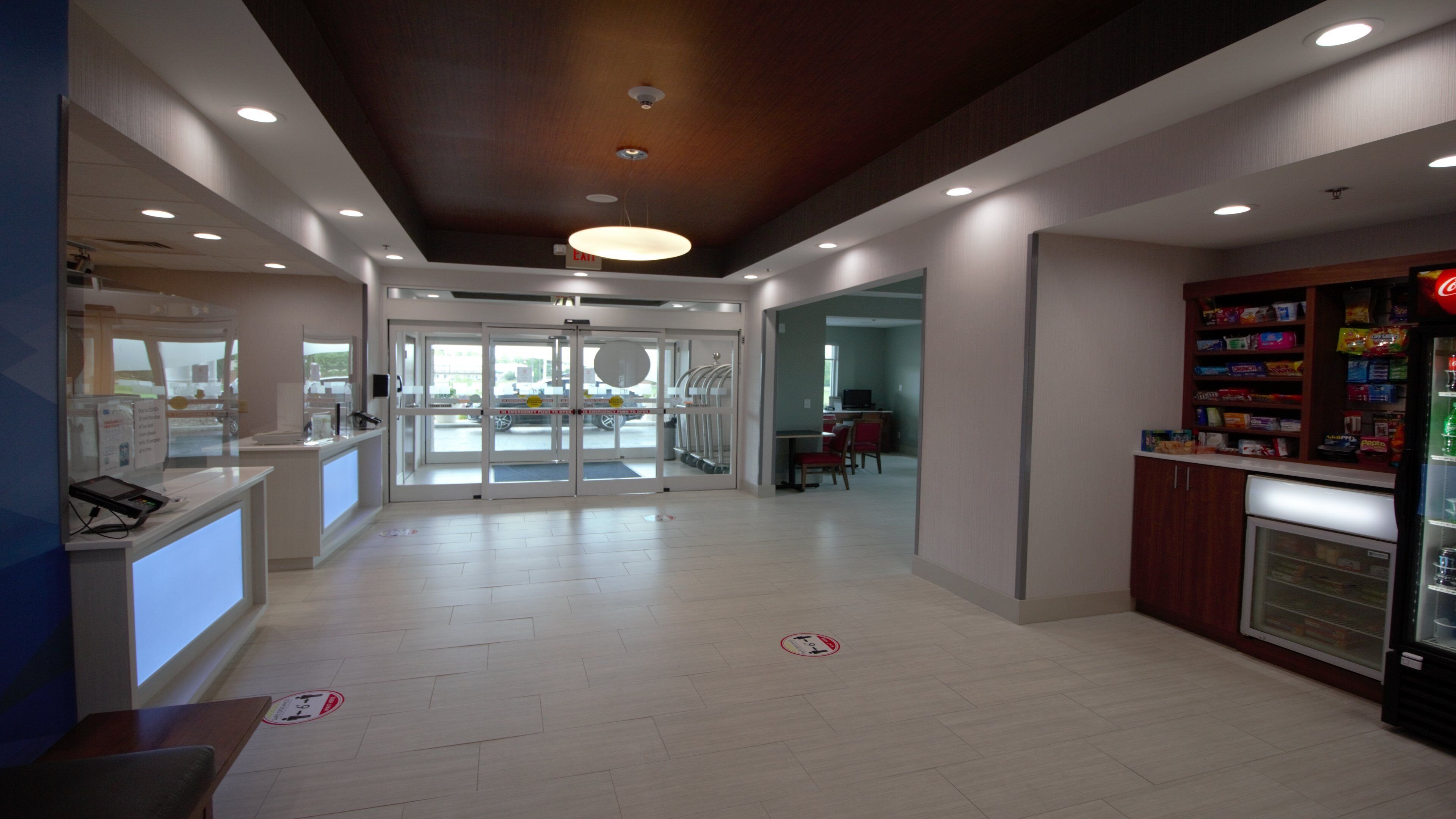 A spacious indoor area with a reception desk, a vending machine, and a seating area with tables and chairs.