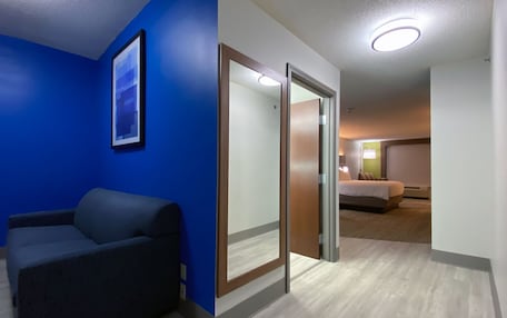 A hotel room with a blue accent wall, a bed, a desk, and a chair.