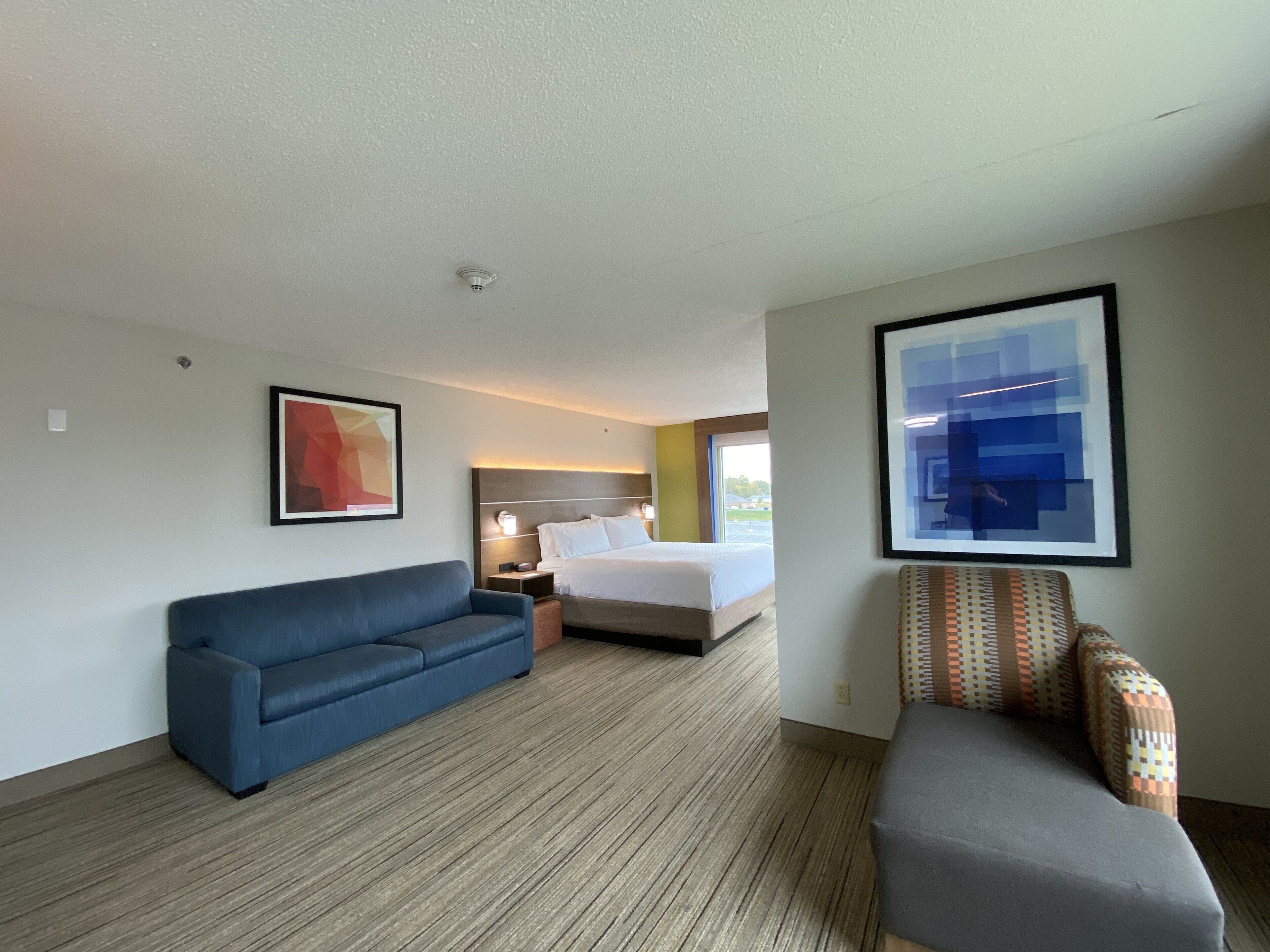 Ein Hotelzimmer mit einem Bett, einem blauen Sofa, einem kleinen Tisch und einem Sessel.