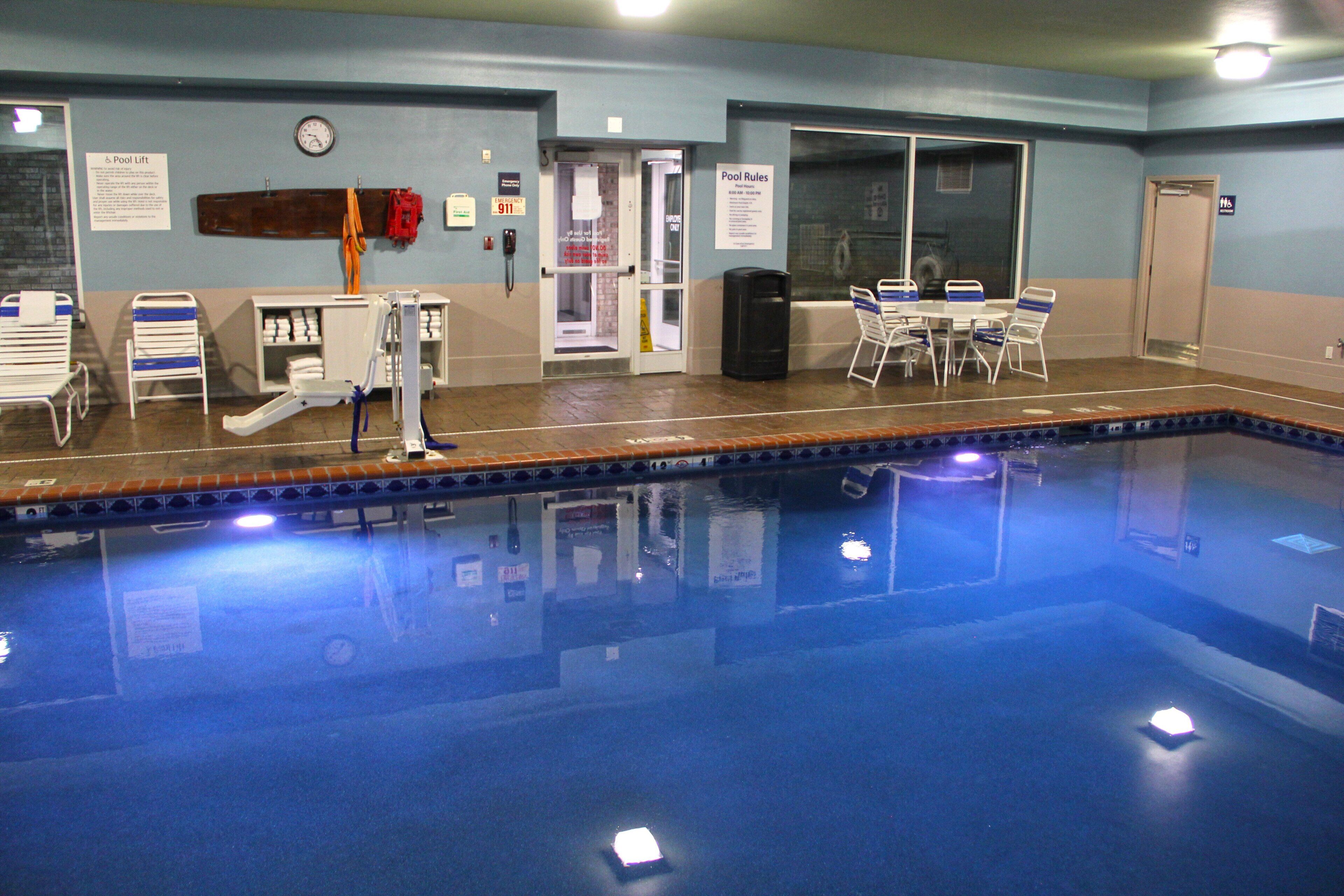 A swimming pool area with a pool lift, changing rooms, and a table with chairs.