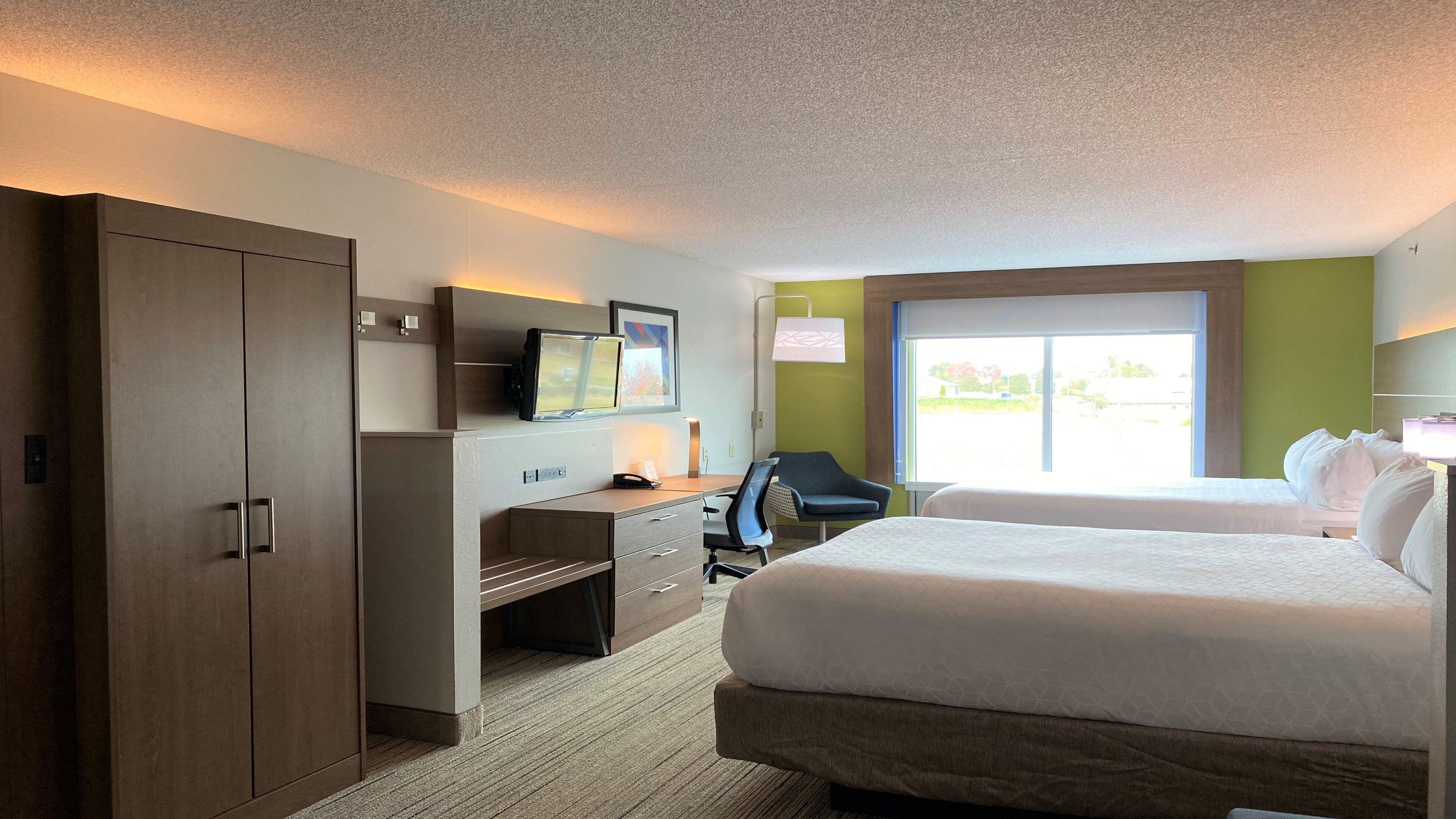 Une chambre d’hôtel équipée d’un lit, d’un bureau, d’une chaise et d’une armoire.