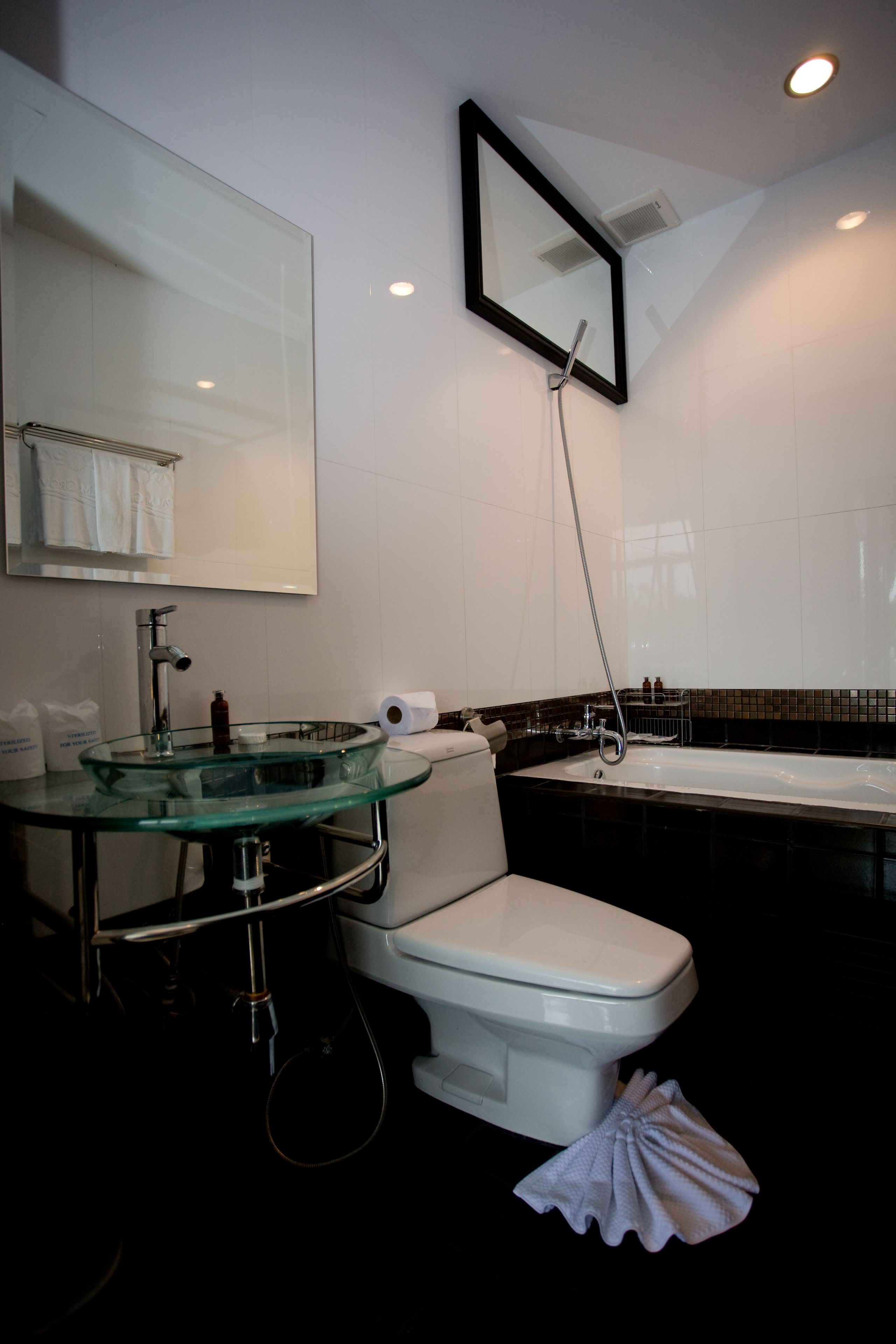 A modern bathroom with a glass sink, white toilet, and a large bathtub.