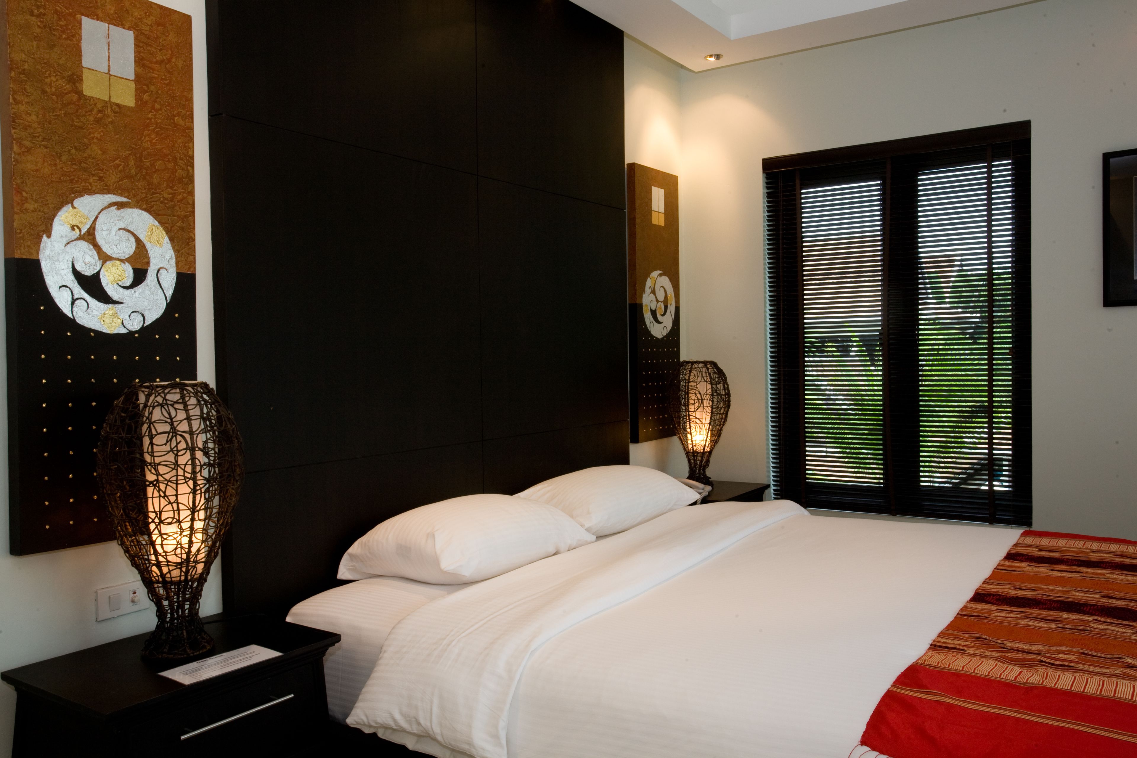 Un dormitorio moderno con una cama grande, cabecera oscura y decoración de pared decorativa.