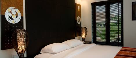 Un dormitorio moderno con una cama grande, cabecera oscura y decoración de pared decorativa.
