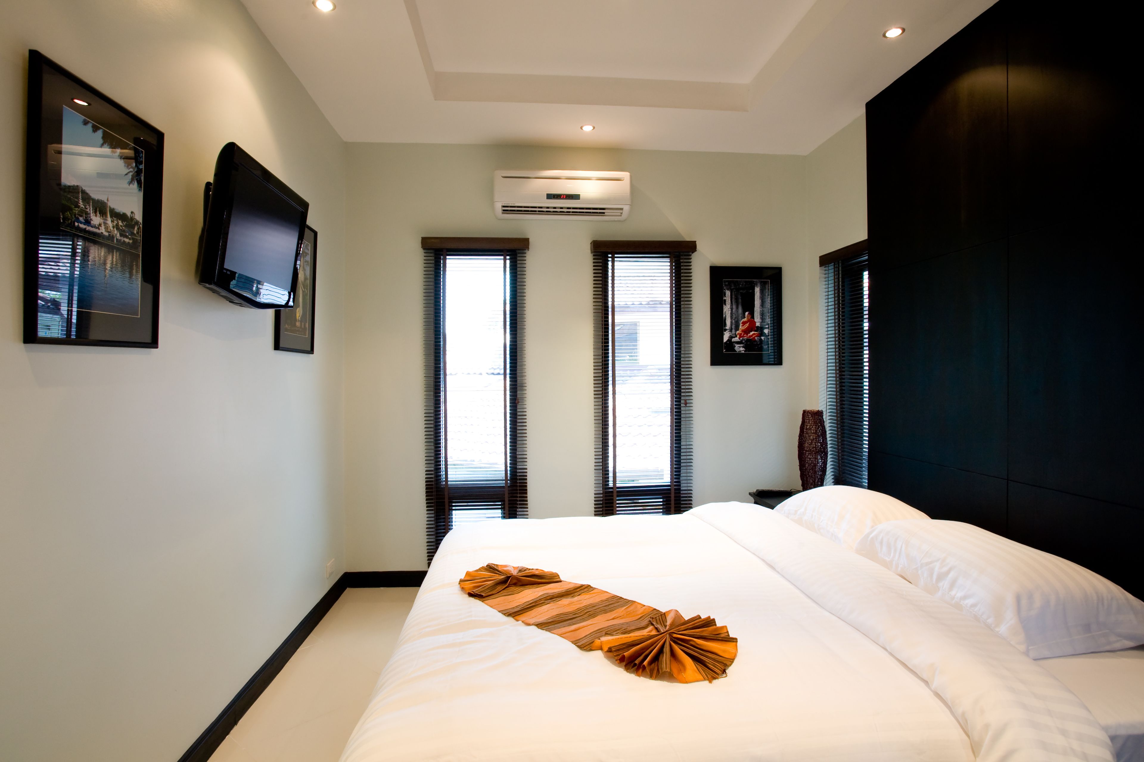 Una habitación de hotel con una cama grande, un televisor de pantalla plana en la pared y un equipo de aire acondicionado.
