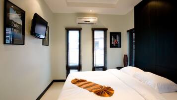 Una habitación de hotel con una cama grande, un televisor de pantalla plana en la pared y un equipo de aire acondicionado.